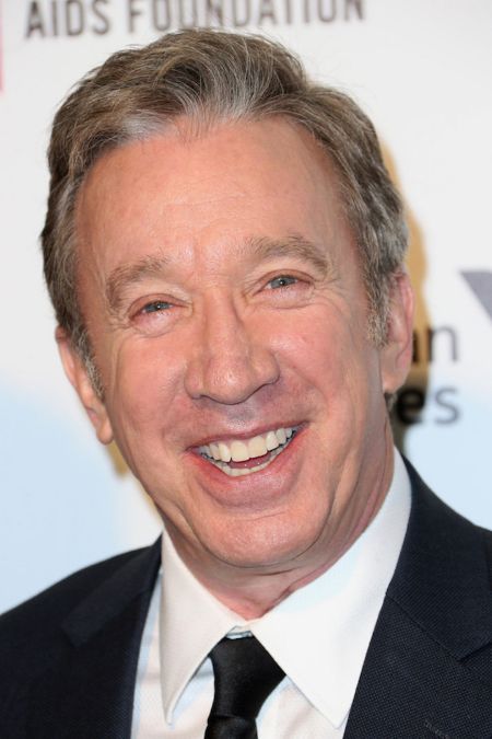 Tim Allen in a black suit poses for a picture.